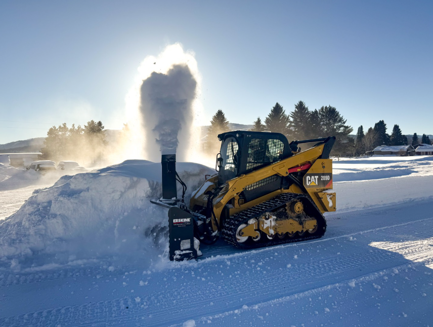 Skid steer snow blower throwing snow into a pile in Edmonton